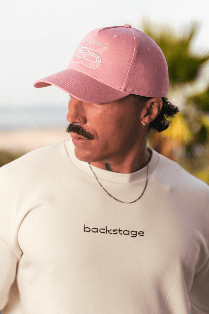 Casquette rose brodée Backstage portée de profil, en extérieur
