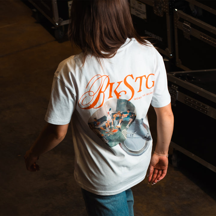 T-shirt streetwear blanc Backstage imprimé badge BKSTG au dos, porté en backstage de soirée