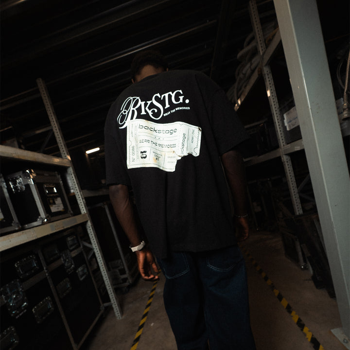 T-shirt streetwear noir Backstage imprimé ticket au dos, porté dans les coulisses d'un club